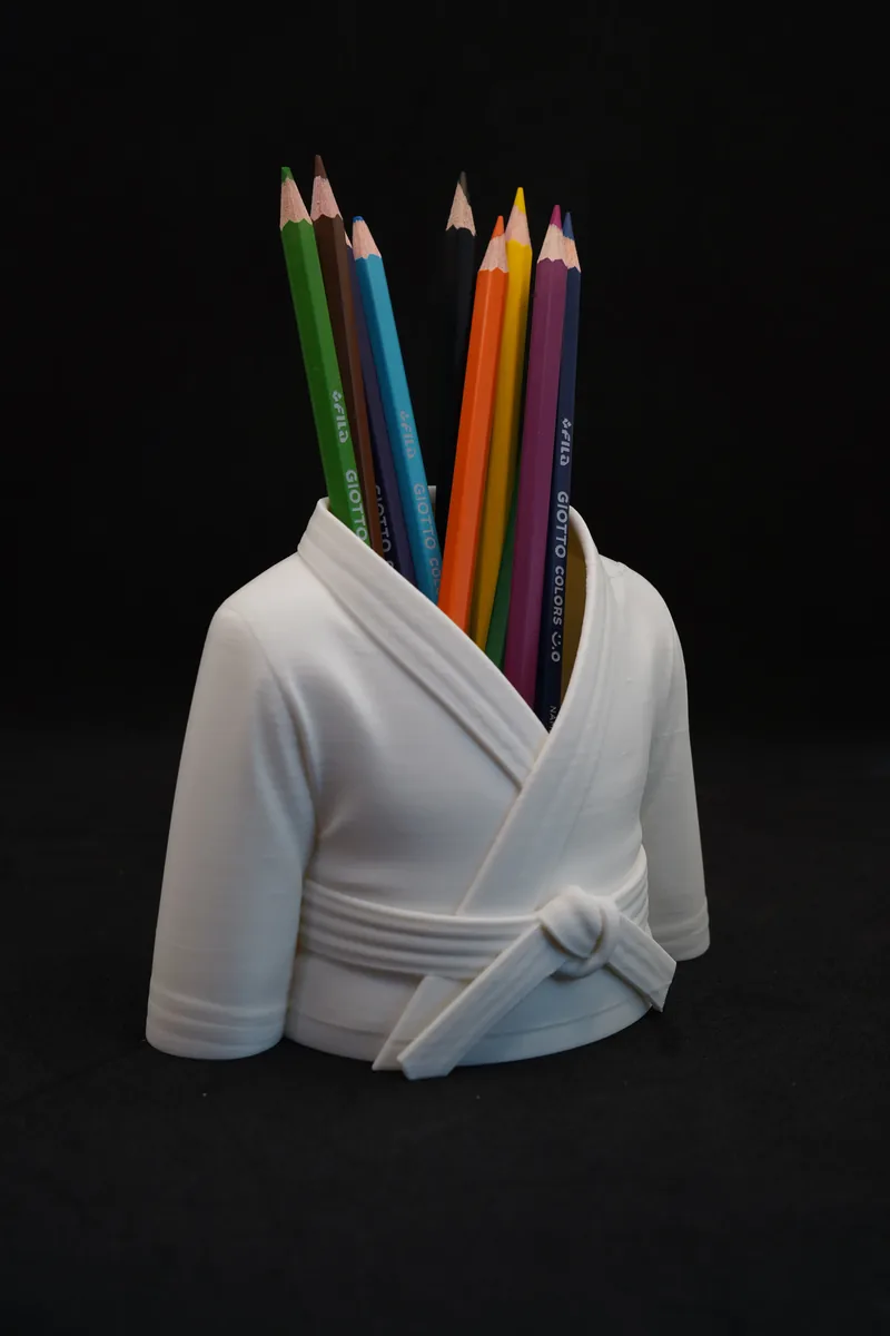 Porta-lápis impresso em 3D em forma de kimono branco com a faixa amarrada, cheio de lápis de cor coloridos.